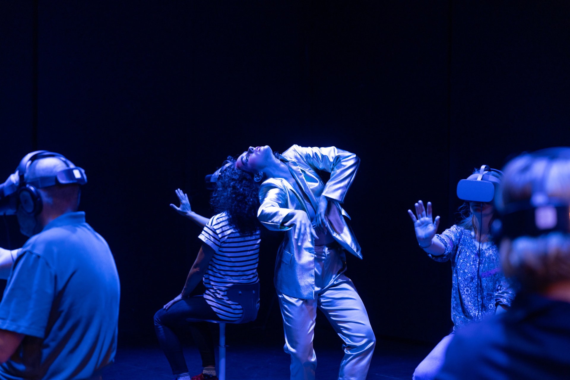 Στιγμιότυπο από το Dancing Audience (2023) της [[#Fabien Prioville Dance Company#]] σε συνεργασία με την [[#En-Knap Group#]] (2023), διαδραστική και εμβυθιστική παράσταση που συνδυάζει ζωντανό χορό και εικονική πραγματικότητα. Οι θεατές και οι θεάτριες φορούν συσκευές VR και εισέρχονται σε εικονικά χορογραφικά περιβάλλοντα, ενώ παράλληλα ζωντανοί/ές επιτελεστές/επιτελέστριες κινούνται στον πραγματικό χώρο και ανταποκρίνονται στις κινήσεις τους.