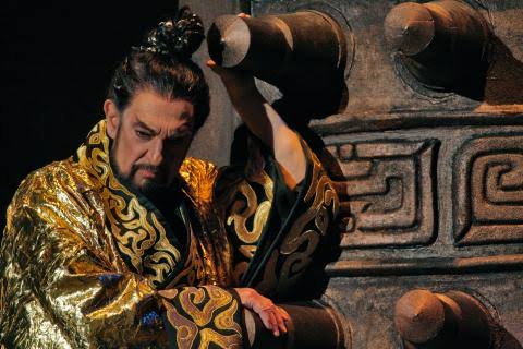 Ο Plácido Domingo [Πλάθιδο Ντομίνγκο] ως αυτοκράτορας Τσιν στον Πρώτο αυτοκράτορα [The First Emperor] του Ταν Ντουν [Tan Dun], λιμπρέτο Χα Τζιν [Ha Jin] και Ταν Ντουν, σκηνοθεσία Ζανγκ Γιμόου [Zhang Yimou], κοστούμια Έμι Γουάντα [Emi Wada] (Metropolitan Opera, Νέα Υόρκη, 2006 – 2007). Διαπολιτισμικότητα στη σύγχρονη όπερα: κινεζικά κρουστά και έγχορδα εντός συμφωνικής ορχήστρας, φωνητική της όπερας του Πεκίνου δίπλα στο δυτικό μπελκάντο, με Κινέζους δημιουργούς να αναμορφώνουν το είδος σε κεντρικό δυτικό θεσμό. Φωτογραφία: Ken Howard / Metropolitan Opera, 2007.