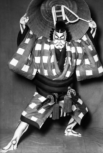 [[#Ονόε Κικουγκορό ΣΤ΄ [Onoe Kikugorō VI]#]] (1885-1949) στον ρόλο του Ουμεόμαρου [Umeōmaru] στο έργο Καμπούκι Σουγκαουάρα Ντέντζου Τεναράι Καγκάμι [Sugawara Denju Tenarai Kagami, 菅原伝授手習鑑] (α΄ παράσταση: 1746). Στο καμπούκι, ο μονόλογος λαμβάνει τη μορφή του τσουράνε (tsurane): εκτεταμένης ρητορικής απαγγελίας, κατά την οποία ο ηθοποιός ακινητοποιείται σε τυποποιημένη στάση (μιέ / mie) και εκφωνεί τον λόγο του με υψηλά στυλιζαρισμένη φωνητική τεχνική, αναδεικνύοντας μια παράδοση μονολόγου ριζικά διαφορετική από τη δυτική. Φωτογραφία αγνώστου, προ του 1949. Εθνικό Θέατρο Ιαπωνίας, ψηφιακή βιβλιοθήκη.