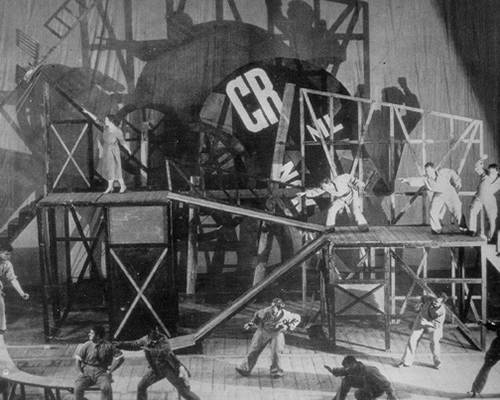 Στιγμιότυπο από την παράσταση ο Υπέροχος Κερατάς του Κρόμελινκ σε σκηνοθεσία [[#Vsevolod Meyerhold#]] και σκηνογραφία [[#Liubov Popova#]] (Μόσχα, 1922˙ Ρωσικός Κονστρουκτιβισμός).