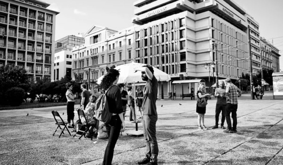 Στιγμιότυπο της περιπατητικής παράστασης θεάτρου τεκμηρίωσης Στη μέση του δρόμου του Πρόδρομου Τσινικόρη, βασισμένη σε έρευνα για τους αστέγους της Αθήνας: το κοινό, εξοπλισμένο με συσκευές αναπαραγωγής ήχου και ακουστικά, ακολουθούσε καθορισμένη διαδρομή και ερχόταν σε επαφή με προσωπικές αφηγήσεις. Εθνικό Θέατρο, Πειραματική Σκηνή, 2015. 