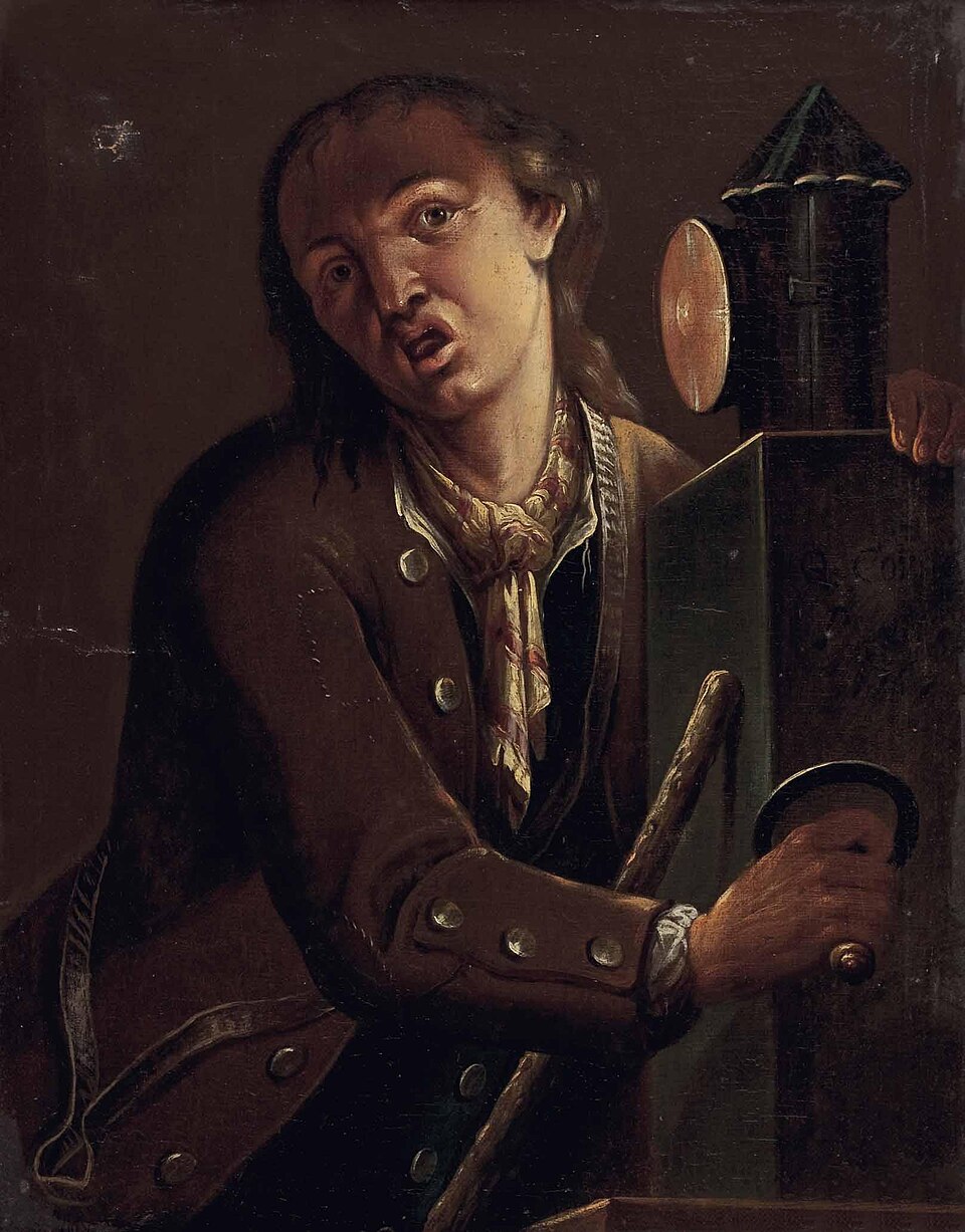 Ζωγραφική απεικόνιση ενός κράχτη/θιασάρχη (τελάλη) που παρουσιάζεται να χρησιμοποιεί τον «Μαγικό Φανό» [Lanterna/Laterna Magica], στη Γερμανία του 18ου αιώνα. Το έργο, αγνώστου καλλιτέχνη, αποτυπώνει μια σκηνή λαϊκής ψυχαγωγίας και πρώιμης οπτικής προβολής εικόνων στο κοινό.