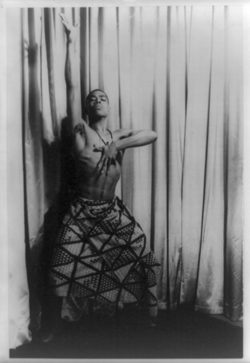 Πορτρέτο του [[#Alvin Ailey [Άλβιν Έιλυ]#]] από τον φωτογράφο [[#Carl Van Vechten [Καρλ Βαν Βέχτεν]#]]. Ο Έιλι υπήρξε κορυφαίος δημιουργός του&nbsp;μοντέρνου χορού, ο οποίος ενσωμάτωσε στη χορογραφία του στοιχεία από την αφροαμερικανική παράδοση, το γκόσπελ και την τζαζ, αναδεικνύοντας τη σωματικότητα ως μέσο κοινωνικής και πολιτισμικής έκφρασης. Η φωτογραφία (εκτύπωση ζελατινοαργύρου) ανήκει στην ιστορική συλλογή του Carl Van Vechten στη Βιβλιοθήκη του Κογκρέσου [Library of Congress], αποτυπώνοντας τη δυναμική προσωπικότητα του καλλιτέχνη που σφράγισε το παγκόσμιο χορευτικό ρεπερτόριο με έργα-σταθμούς όπως το&nbsp;Revelations&nbsp;(1960).