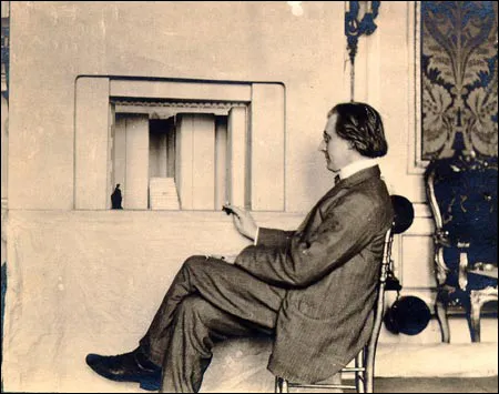 Ο Edward Gordon Craig μπροστά σε σκηνογραφική μακέτα με σκηνικά παραπετάσματα, Arena Goldoni, Φλωρεντία, 1912. Η μακέτα λειτουργούσε ως εργαλείο δοκιμής των διατάξεων των πτυσσόμενων φύλλων πριν από τη μεταφορά τους στη σκηνή.