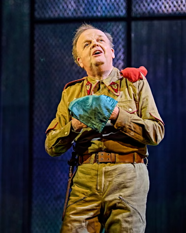 Ο [[#Toby Jones [Τόμπυ Τζόουνς]#]] ως Ιάγος κρατά το μοιραίο μαντήλι στον Οθέλλο [Othello] του [[#William Shakespeare [Ουίλλιαμ Σαίξπηρ]#]], σε σκηνοθεσία του [[#Tom Morris [Τομ Μόρρις]#]] (Theatre Royal Haymarket, Λονδίνο, 2025). Το μαντήλι είναι το κατεξοχήν σκηνικό αντικείμενο-παγίδα της τραγωδίας: από ερωτικό δώρο του Οθέλλου στη Δυσδαιμόνα μετατρέπεται, στα χέρια του Ιάγου, σε πλαστό «τεκμήριο» απιστίας που πυροδοτεί τον φόνο.